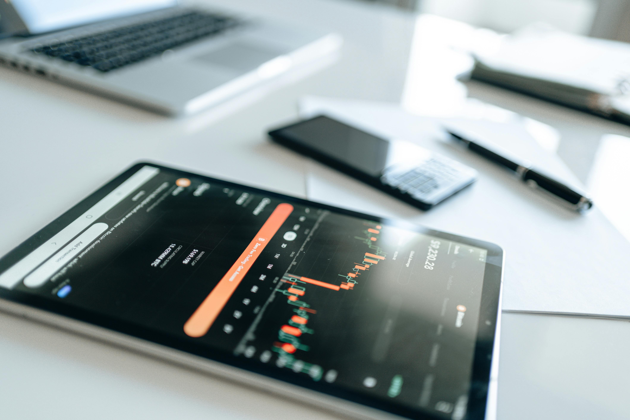 Modern financial tools including tablet with market trends on white desk setup.
